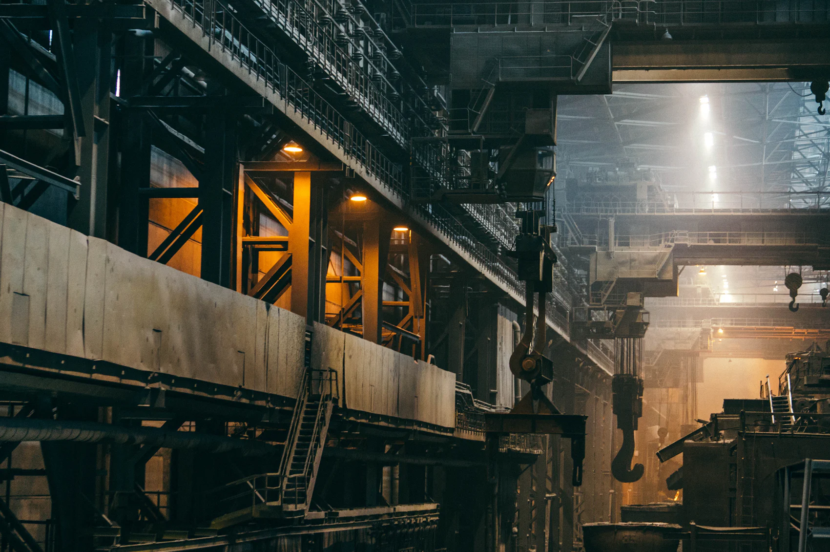 Interior of a steel mill with overhead crane hooks suspended above the shop floor