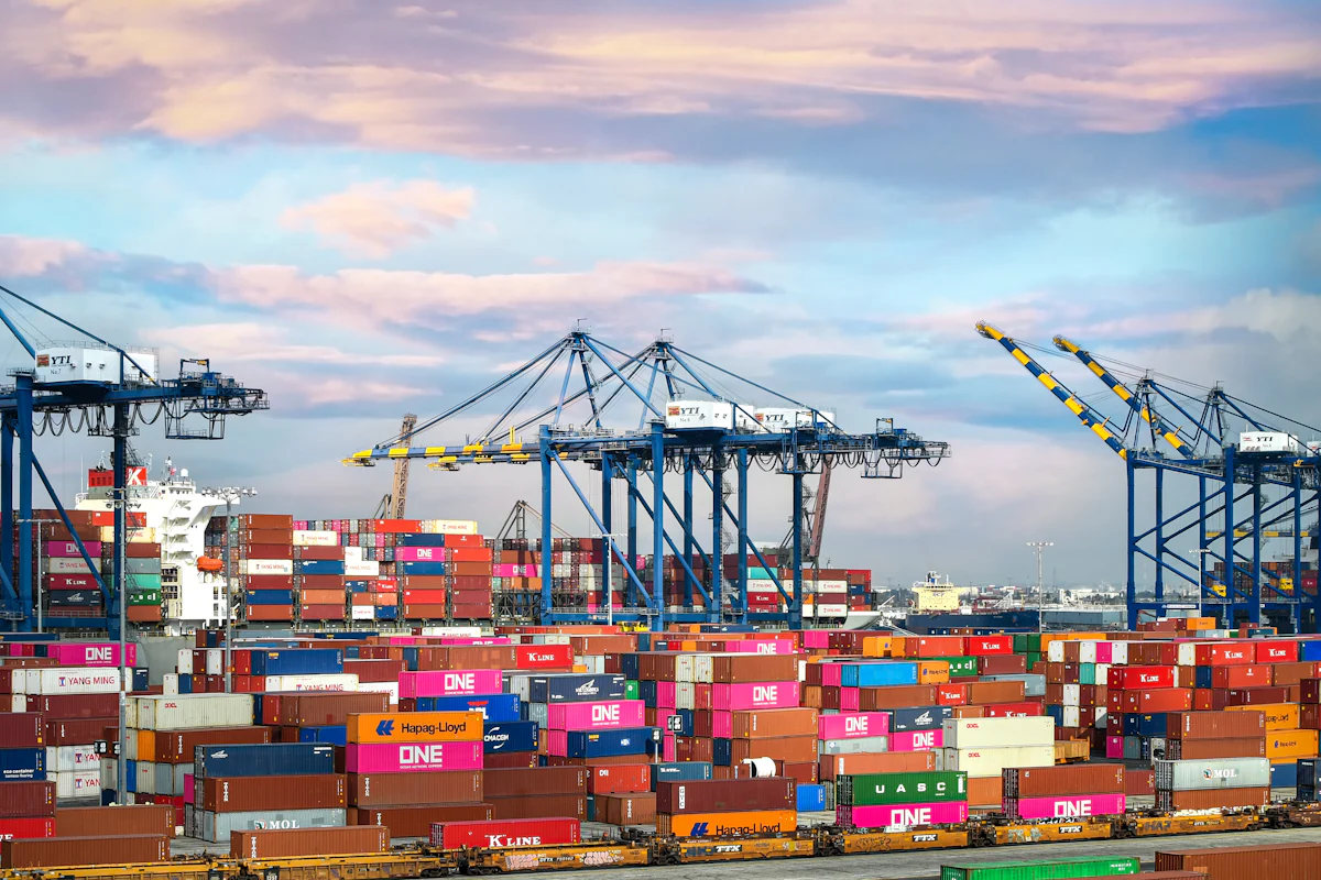 Container port at dusk with stacked shipping containers and gantry cranes